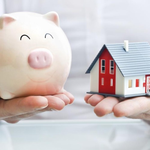 house and a piggy bank in hands