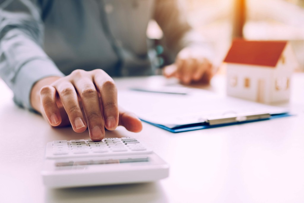 Personne assise à un bureau, effectuant des calculs sur une calculatrice - Multi-Prêts Hypothèques